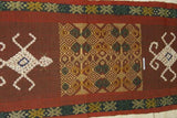 Hand woven ceremonial Sumba Hinggi Ikat Songket Textile 55"x 13.25" Geometric Designs. Handspun Cotton Tapestry, Dyed with Natural Pigments. Adorned with Symbolic Insect Motifs Created with Hand sewn tiny Nassa Shells (SR26) red rust background